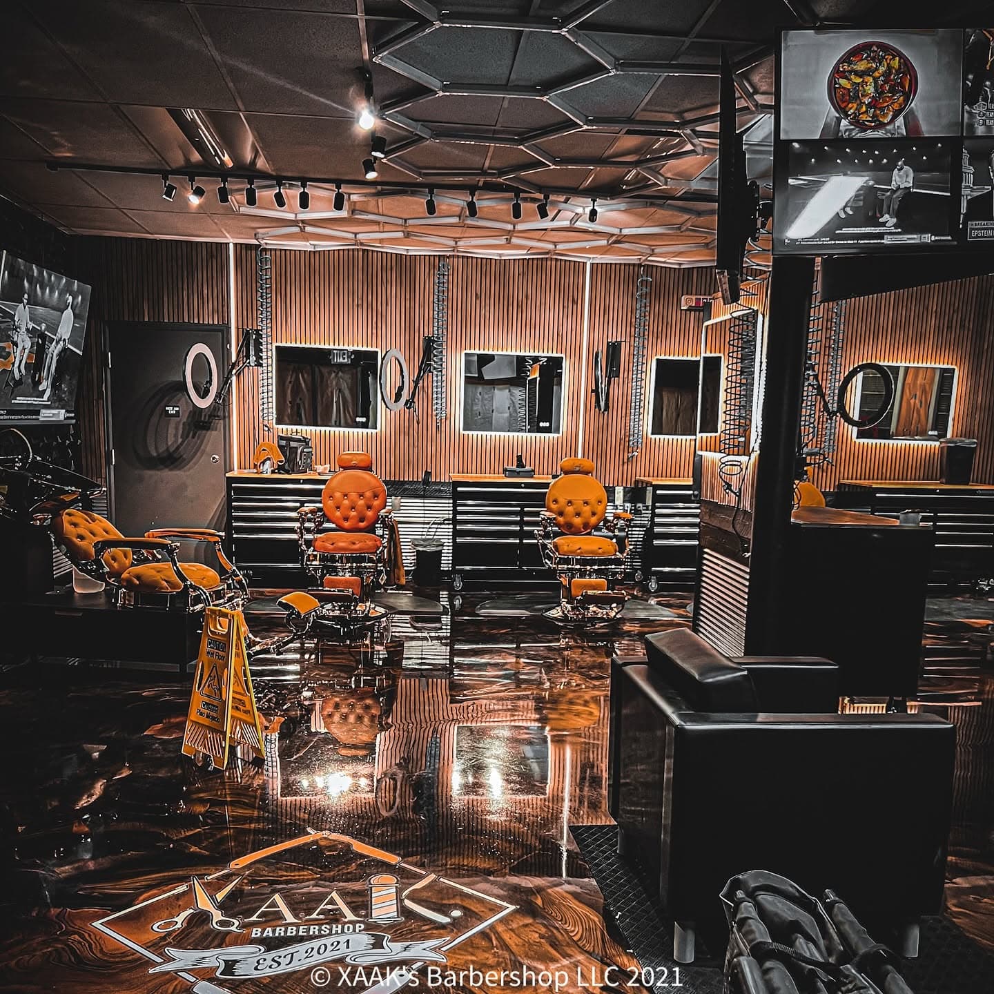 Inside XAAK's Barbershop — orange chairs, wood-slat walls, ring lights
